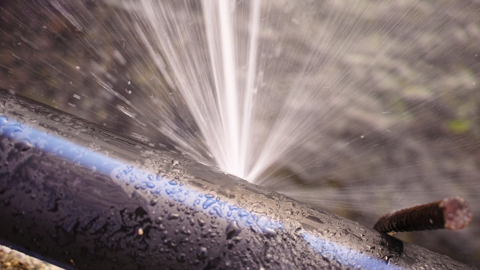 Water spraying forcefully from a damaged metal pipe